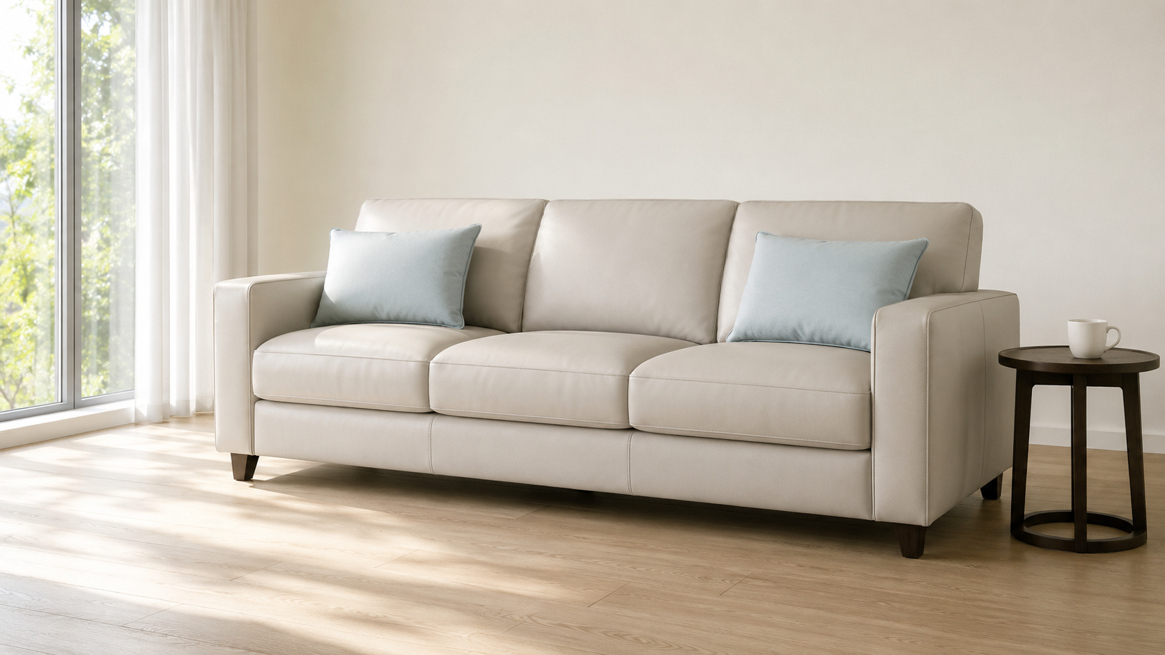淺灰米白平滑面科技皮三人座沙發,靠背放粉藍色長方靠墊,自然光客廳實景